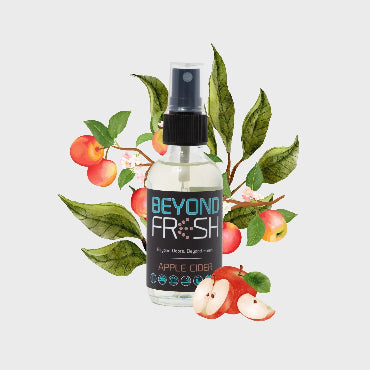 Bottle of 'Beyond Fresh' Apple Cider scented spray with apples and leaves on a white background.
