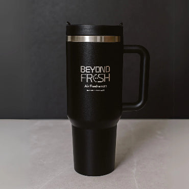 Front side of black stainless steel tumbler with silver laser-engraved branding on marble surface.