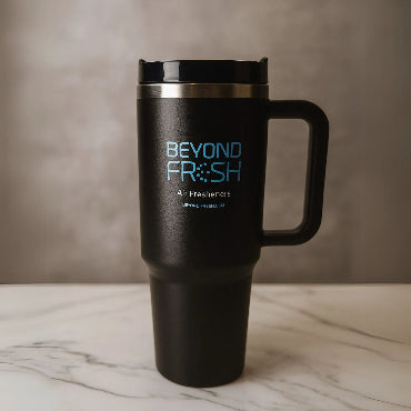 Front side of black stainless steel tumbler with blue 'Beyond Fresh' branding on a marble surface.