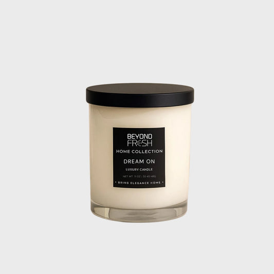 Candle with a black lid and label on a marble surface, Dream On scent on a white background.