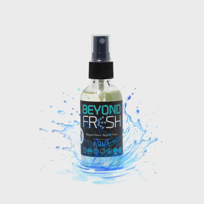 Bottle of 'Beyond Fresh' Aqua scented spray with a splash of water on a white background.