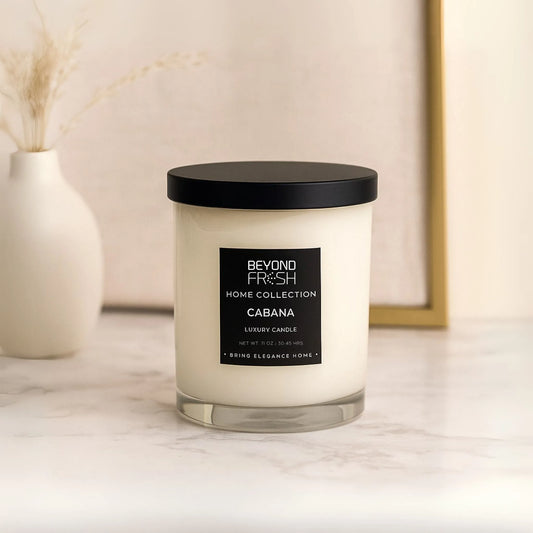 Candle with a black lid and label on a marble surface, Cabana scent with a neutral background