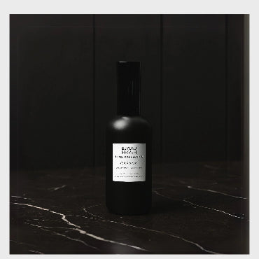 100 ml black bottle of Home Collection Room Spray, Cabana scent on a dark marble surface.