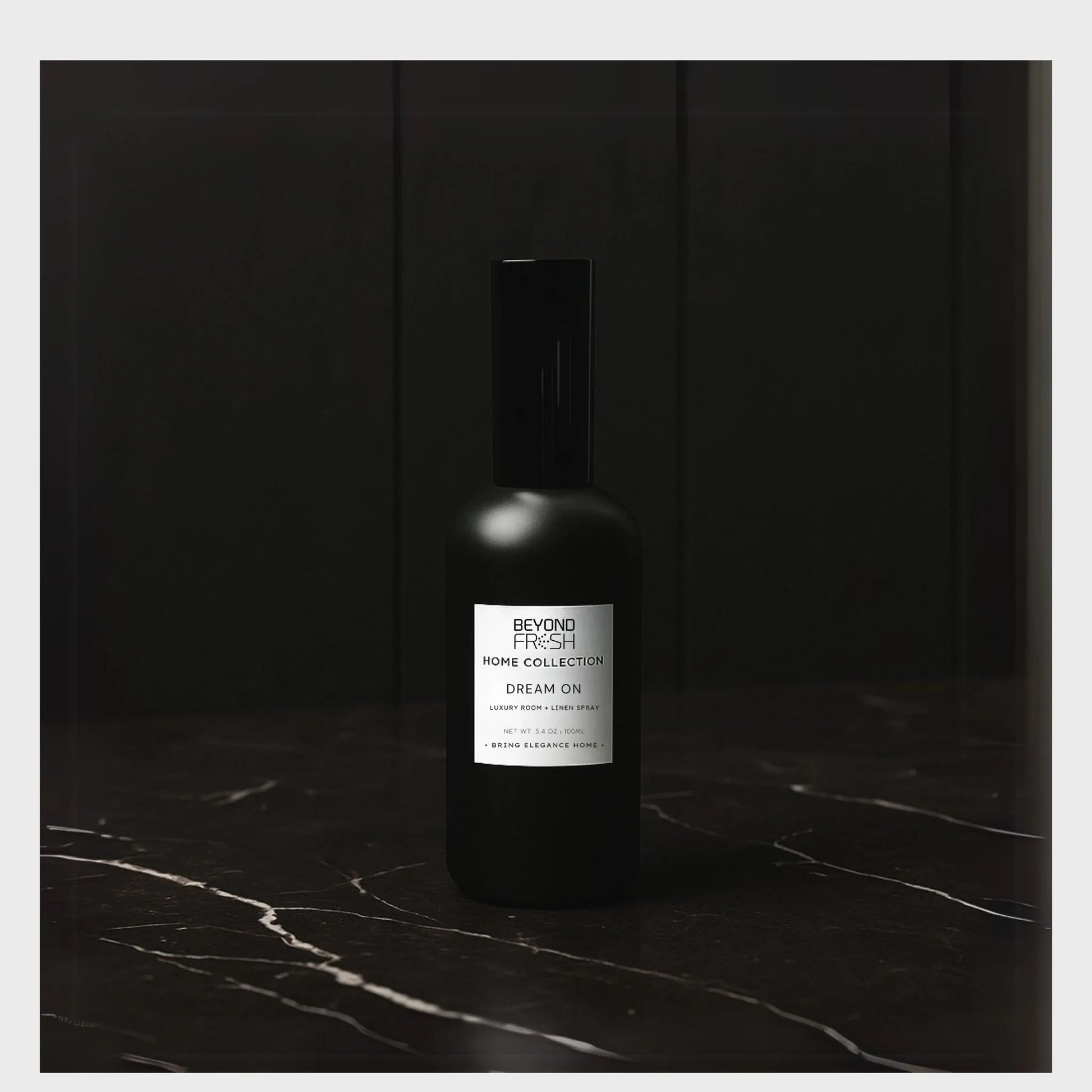 100 ml black bottle of Home Collection Room Spray, Dream On scent on a dark marble surface