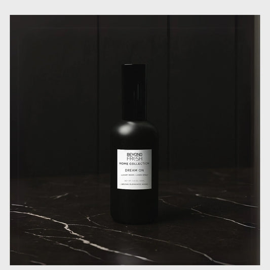 100 ml black bottle of Home Collection Room Spray, Dream On scent on a dark marble surface