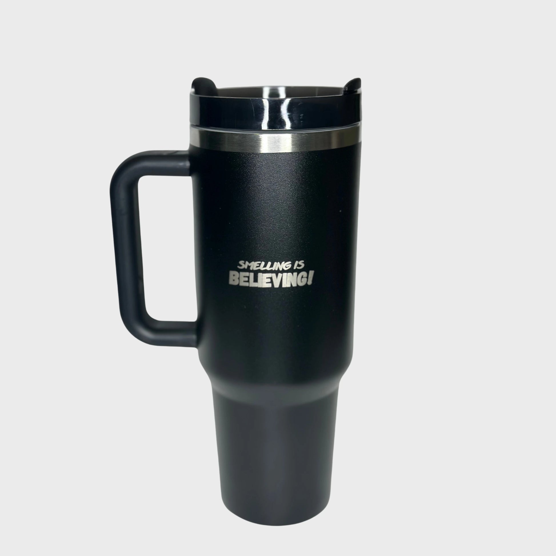 Black tumbler with 'SMELLING IS BELIEVING!' text on a light gray background
