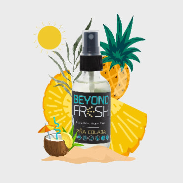 Bottle of Pina Colada scented spray with pineapples and coconuts around it on a white background.