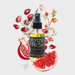 Bottle of 'Beyond Fresh' Pomegranate scented spray with fruits and leaves on a white background.