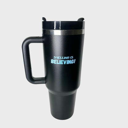 Black travel tumbler with 'Smelling is Believing!' text on a light gray background
